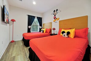 A hotel room with two beds, red bedding, Mickey Mouse wall art, and a red floor lamp. - Remodeled home, Regal Oaks-September Special Price (Kissimmee)