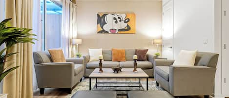 A modern living room with two sofas, a coffee table, and a large painting on the wall.