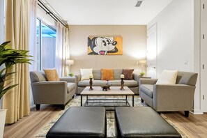 A modern living room with two sofas, a coffee table, and a large painting on the wall. - Resort-style living, heated pool and water slides! (Kissimmee)