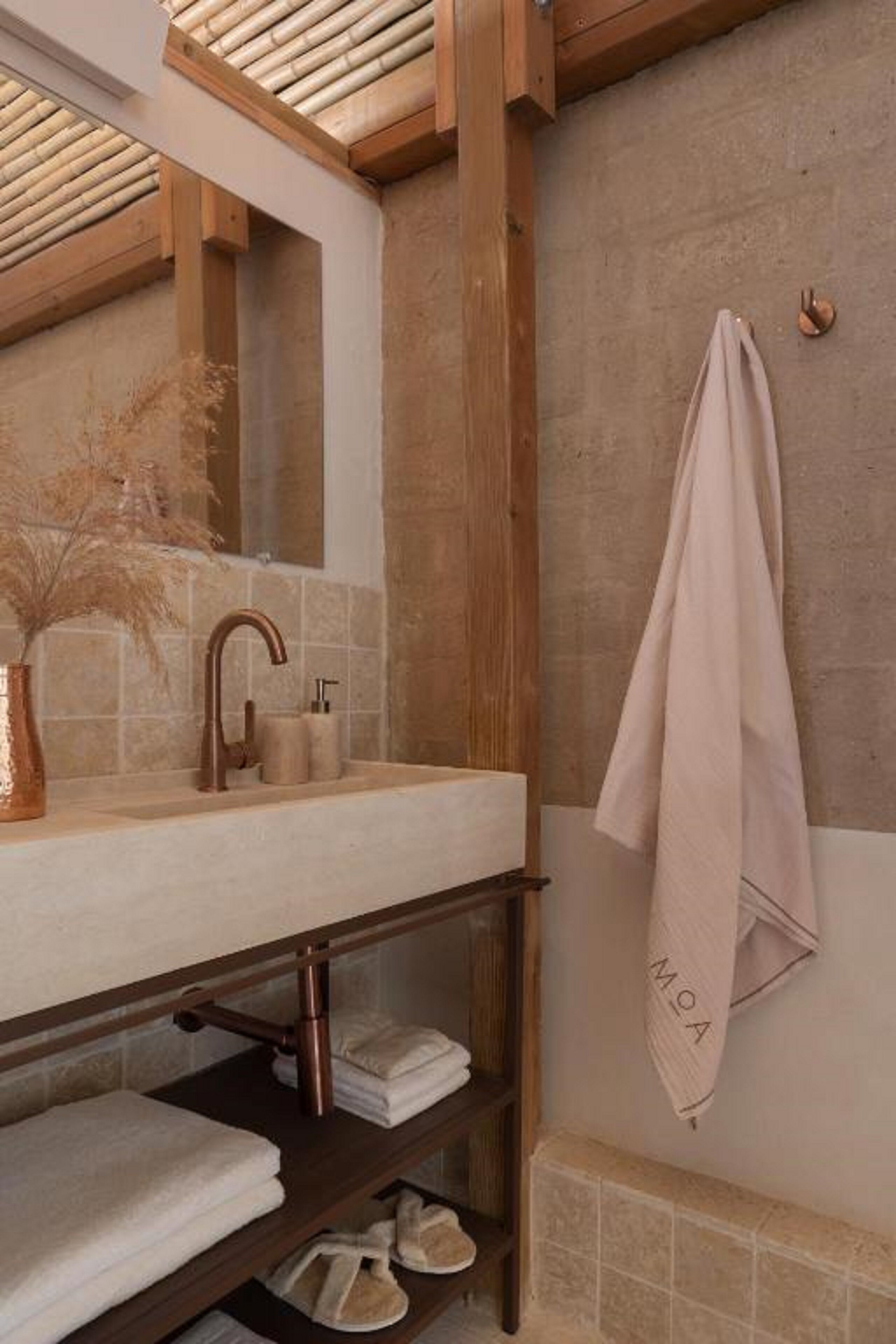 Un baño con tocador de madera, toallero y espejo.
