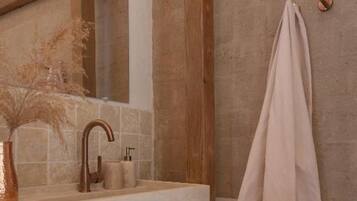 Un baño con tocador de madera, toallero y espejo.
