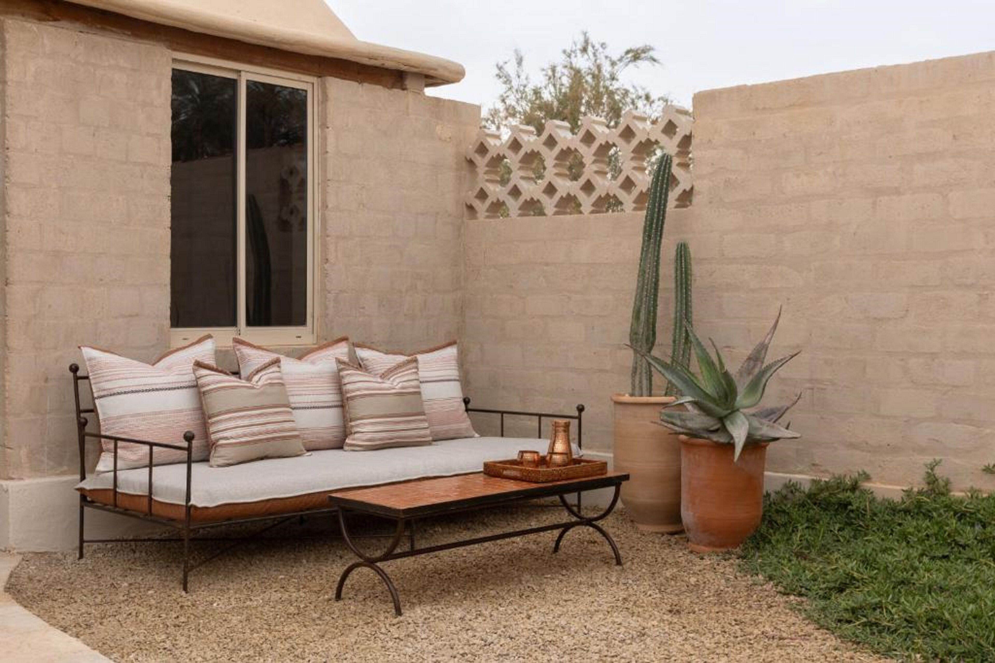 Un rincón exterior acogedor con sofá, una mesita de centro y plantas en macetas.