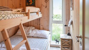 Een kamer met een houten stapelbed, een raam, een klein tafeltje en een decoratief object.