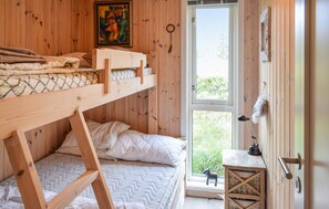Ein Zimmer mit einem hölzernen Etagenbett, einem Fenster, einem kleinen Tisch und einem dekorativen Gegenstand.