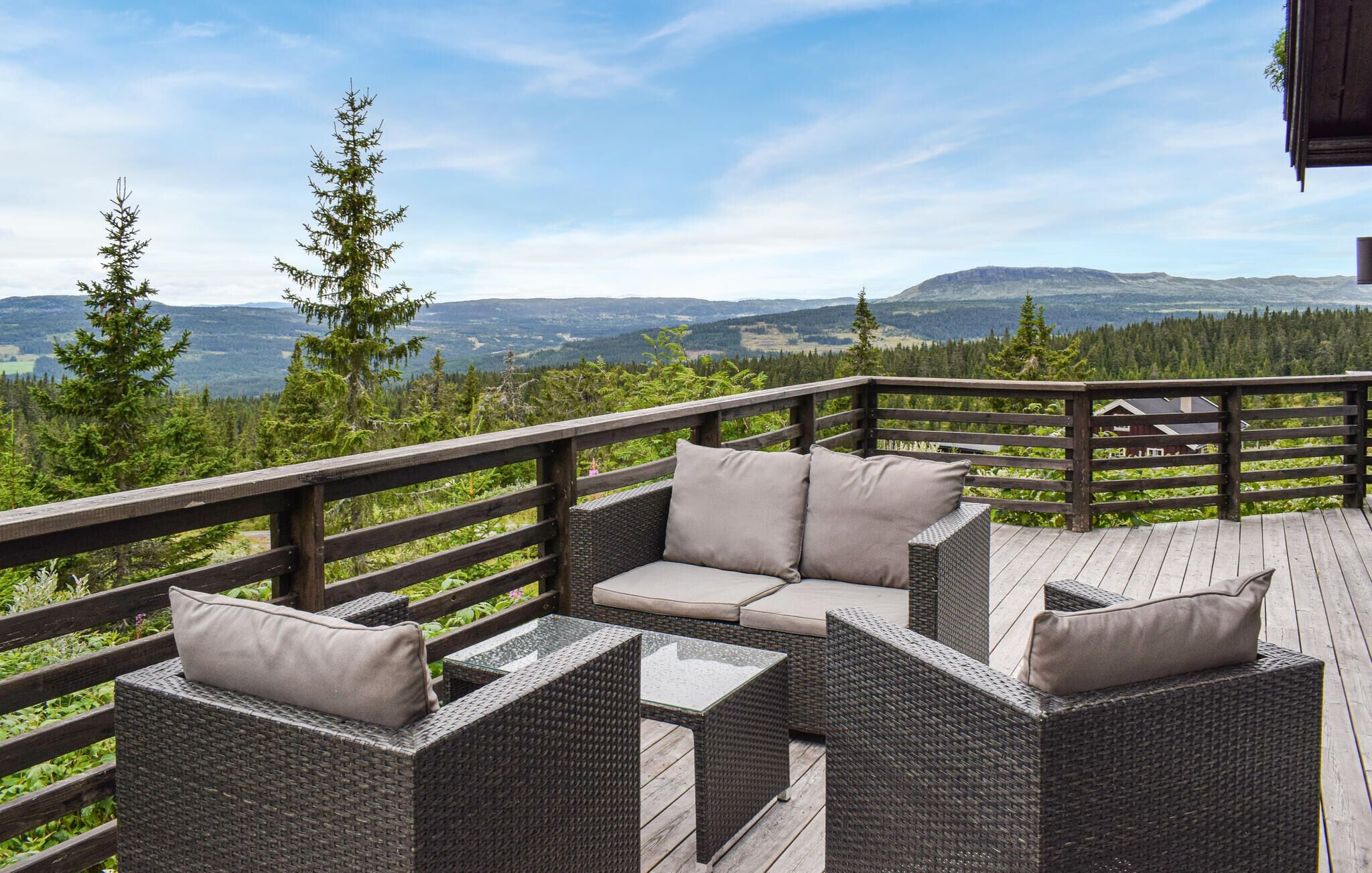 Una terrazza con mobili in vimini e vista su un paesaggio boschivo.