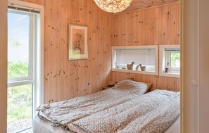 A wooden-paneled room with a bed, a framed picture, and a window with blinds. - Nice home in Tretten with sauna (Tretten)