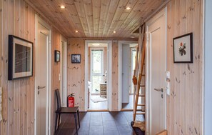 A wooden hallway with framed pictures, a chair, a fire extinguisher, and a ladder. - Nice home in Tretten with sauna (Tretten)