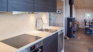 Een moderne keuken met een inbouwfornuis, een roestvrijstalen spoelbak en houten keukenkastjes.