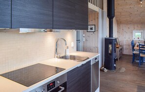 Eine moderne Küche mit Einbauherd, Edelstahlspüle und Holzschränken.