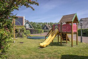 Ein Spielplatz mit Rutsche, Klettergerüst und kleinem Trampolin.