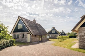 A row of houses with thatched roofs, brick walls, and a paved driveway. - 6-Guest Texel Villa with Sauna & Spa (De Koog)