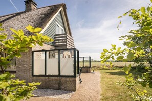 A house with a brick exterior, a thatched roof, and a large glass window. - 6-Guest Texel Villa with Sauna & Spa (De Koog)