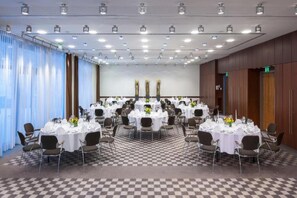 A conference room with round tables, chairs, and a checkered floor.