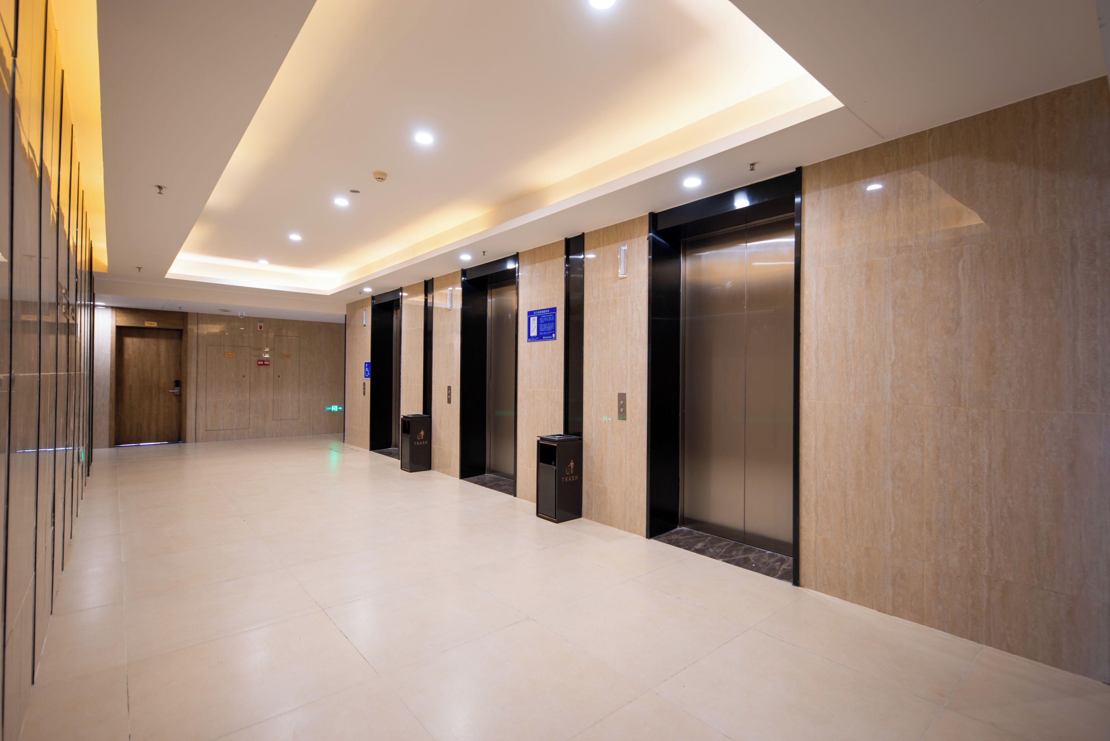 Un moderno vestíbulo de hotel con un largo pasillo, ascensores y una recepción.