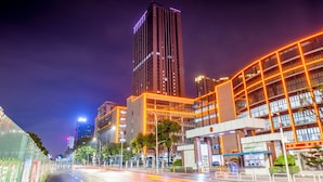 A nighttime cityscape with modern buildings, a clear sky, and a well-lit street.
