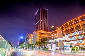 A nighttime cityscape with modern buildings, a clear sky, and a well-lit street.