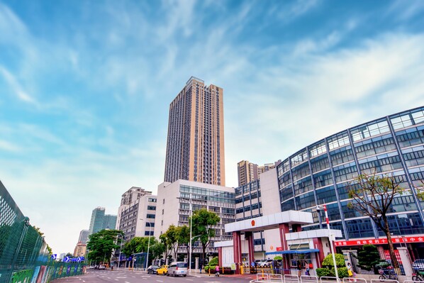 A modern urban street with tall buildings, a clear sky, and a pedestrian crossing.