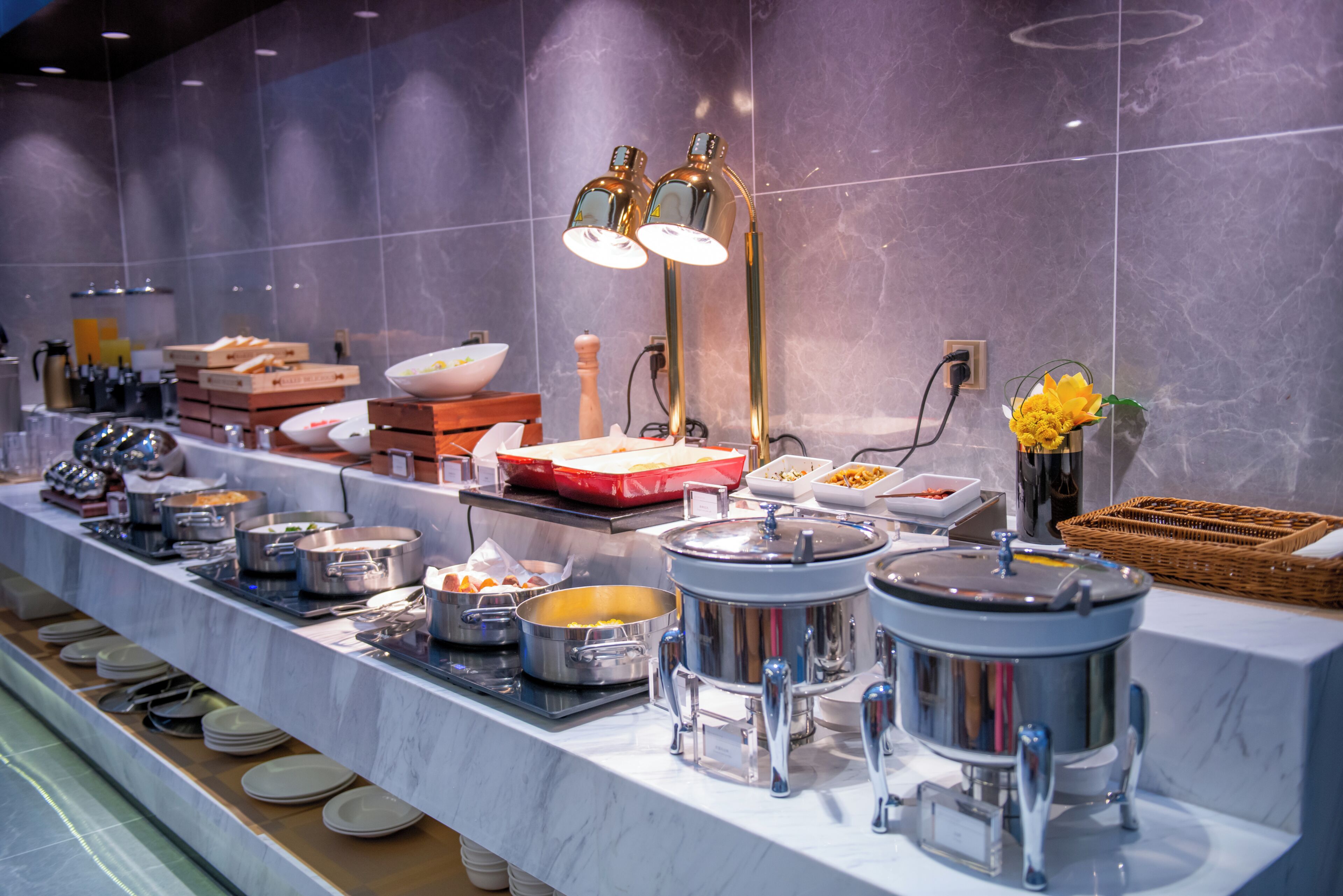 A buffet setup with various food containers and utensils.