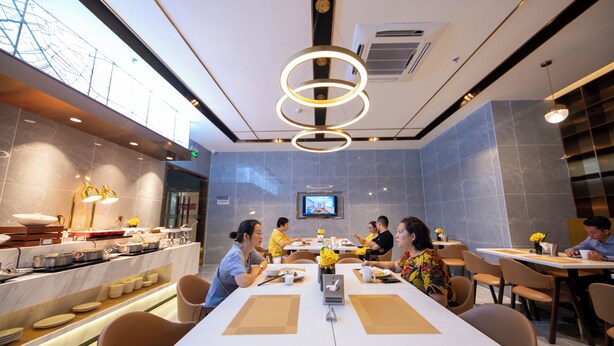 A modern dining area with round tables, a buffet, and a television screen.