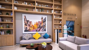 A modern hotel lobby with a large framed cityscape painting, multiple seating areas, and a reception desk.