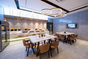 A modern hotel lobby with a seating area, a reception desk, and a television screen.