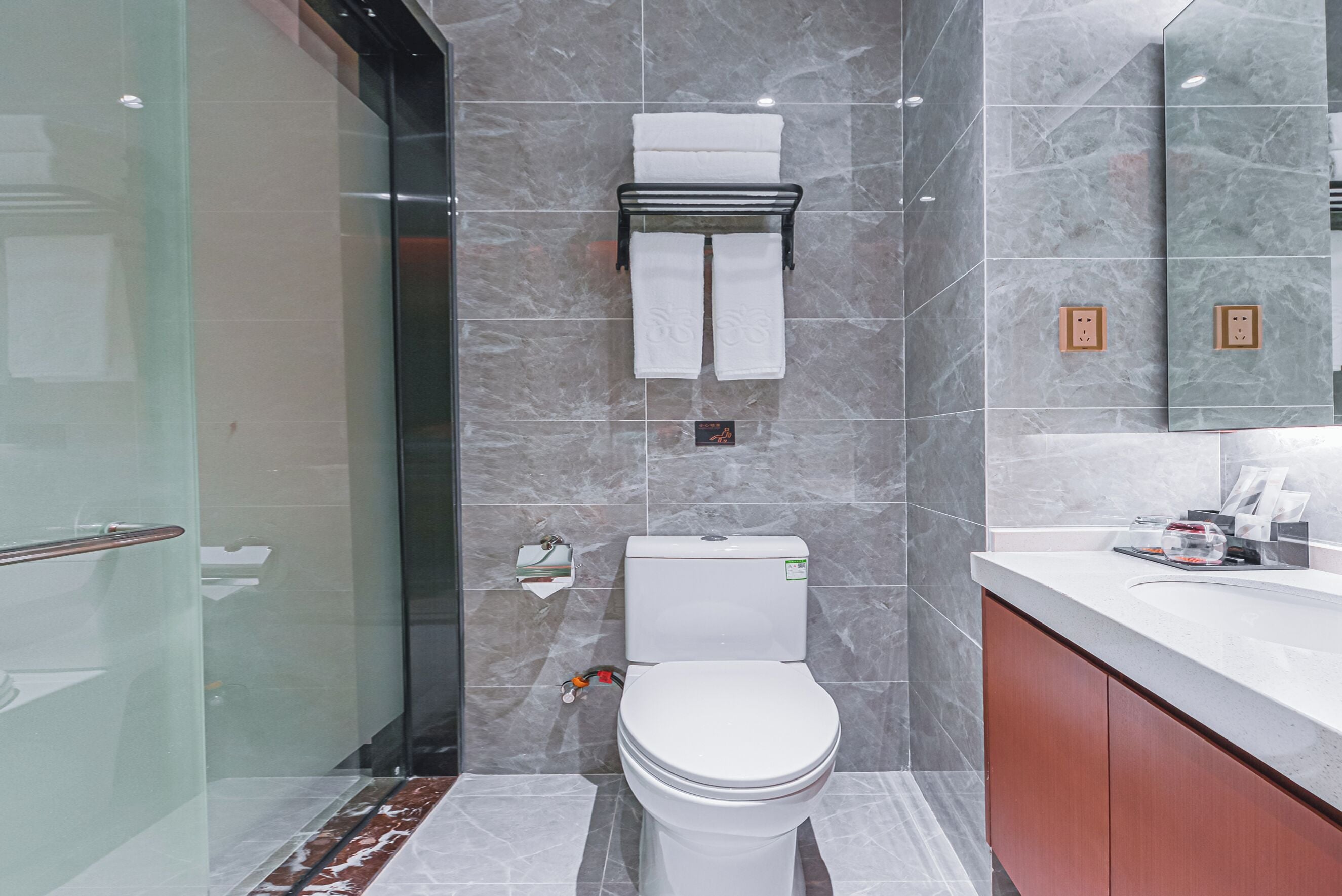 Un baño moderno con cabina de ducha de vidrio, inodoro y tocador con espejo.