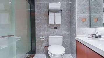 Un baño moderno con cabina de ducha de vidrio, inodoro y tocador con espejo.