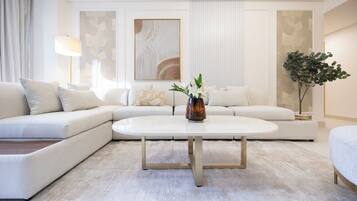 A modern living room with a white sofa, a coffee table, and a vase with flowers.