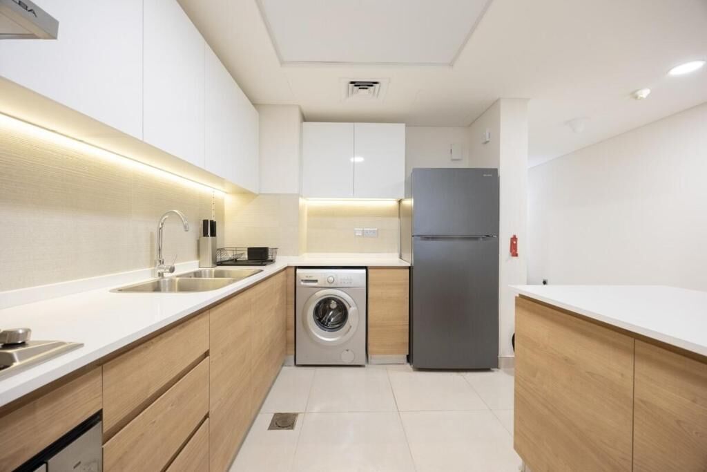 A modern kitchen with a washing machine, a refrigerator, and a sink.