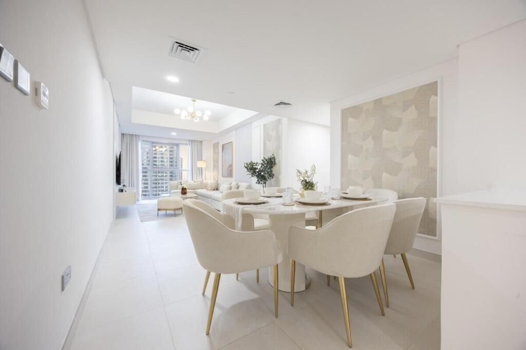 A modern dining area with a round table, white chairs, and a neutral color scheme.