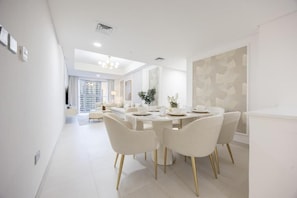 A modern dining area with a round table, white chairs, and a neutral color scheme.