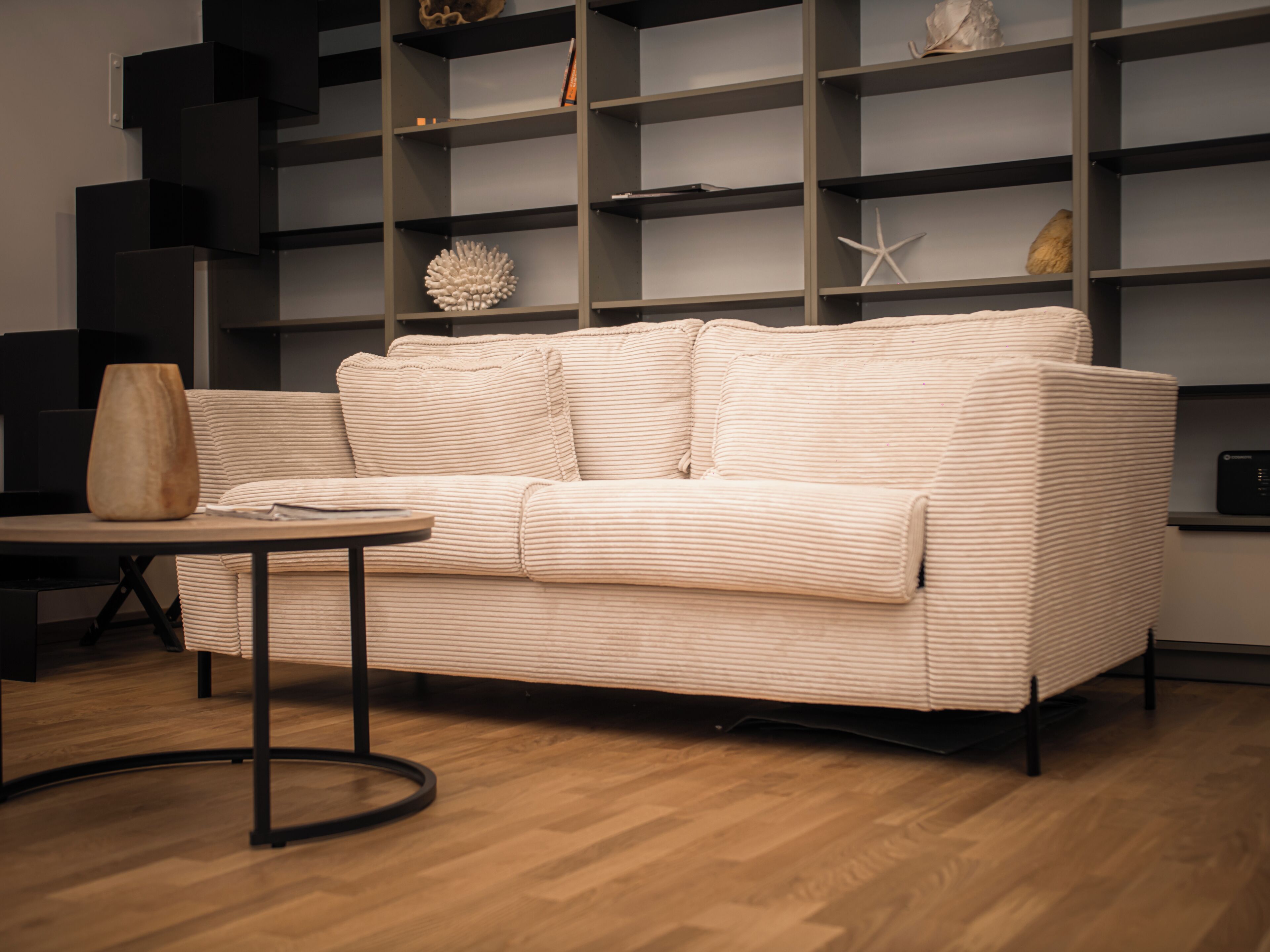 A modern living room with a sofa, a coffee table, and a bookshelf.