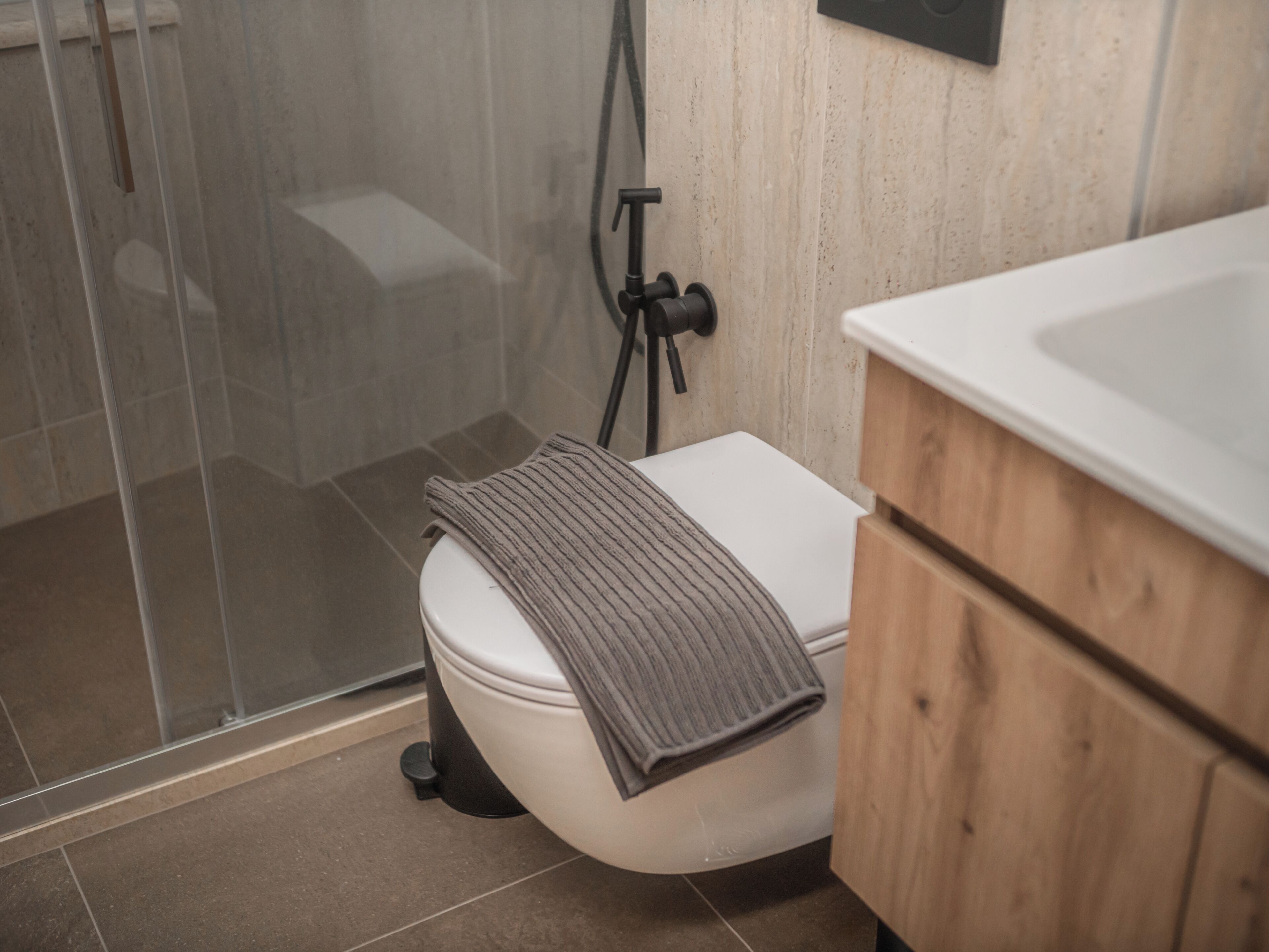 Een badkamer met een wit toilet, een douchecabine en een houten kastje.