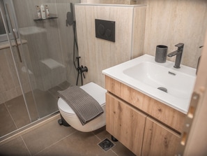 A modern bathroom with a glass shower enclosure, a white toilet, and a wooden vanity with a sink. - The Hidden Passage by LOC Hospitality (Kerkyra)