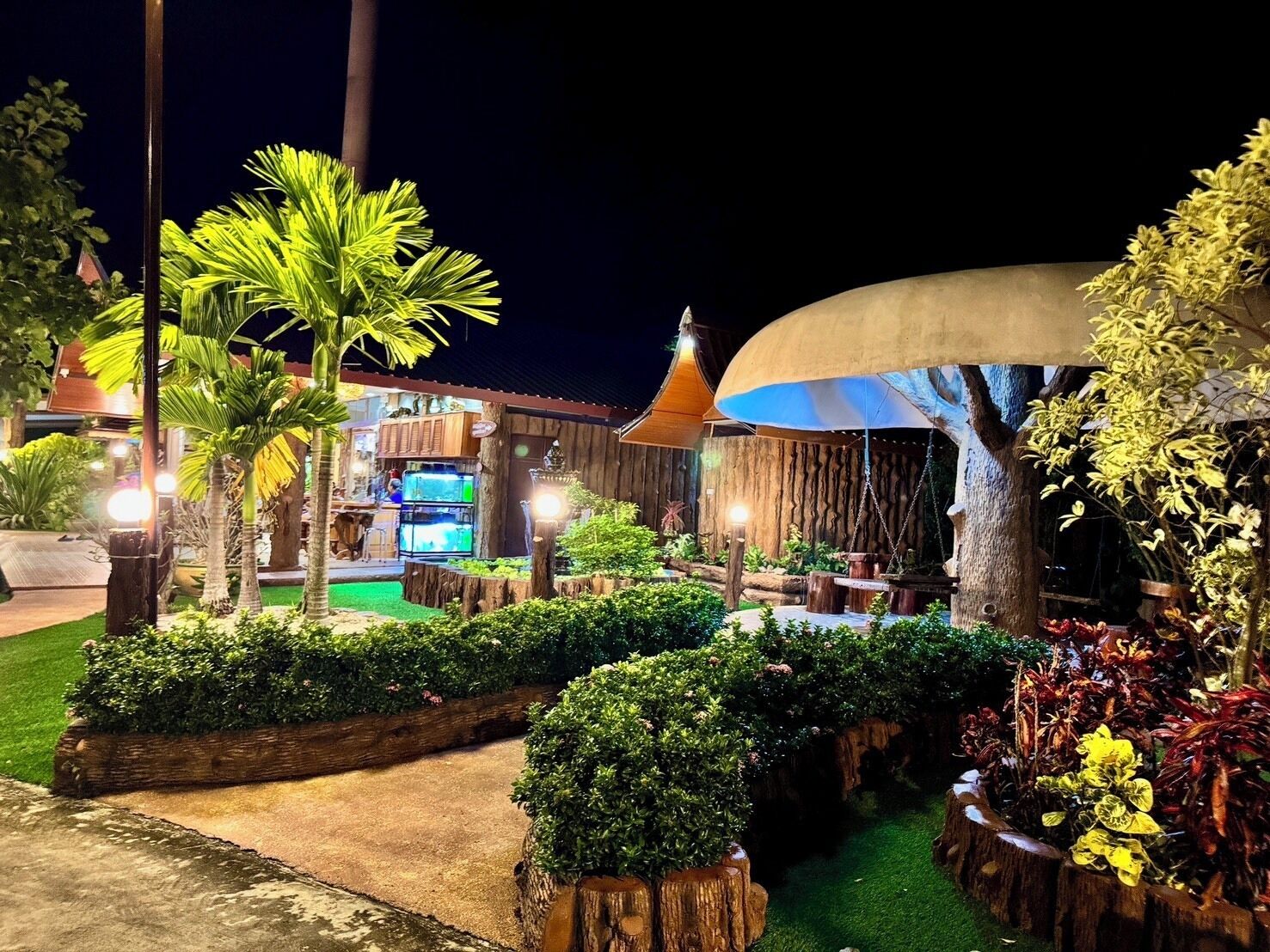 Un espacio al aire libre bien iluminado, con piscina, estructuras de madera y varias plantas.