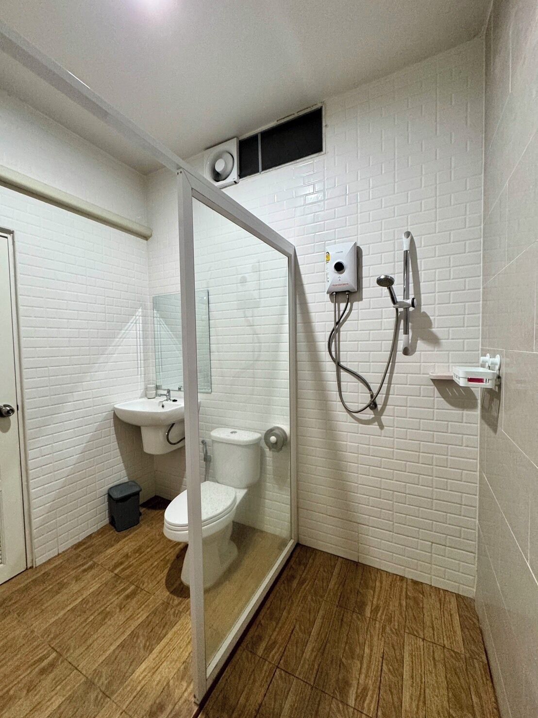 A bathroom with a glass-enclosed shower, a toilet, a sink, and a mirror.