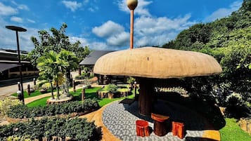 A large mushroom-shaped structure with a spherical top, surrounded by a landscaped garden with various plants and a paved walkway.