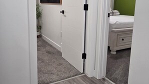 A hallway with a white door, a green wall, and a bed with a green wall in the background. - Cozy 2BR 14mins YYC Airport, University, Banff, Canmore & Entire Home Soft Water (Calgary)