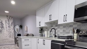A modern kitchen with white cabinets, a black stove, and a patterned backsplash. - Cozy 2BR 14mins YYC Airport, University, Banff, Canmore & Entire Home Soft Water (Calgary)