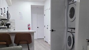 A modern kitchen with a dining area, a washing machine, and a sofa. - Cozy 2BR 14mins YYC Airport, University, Banff, Canmore & Entire Home Soft Water (Calgary)