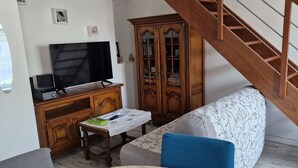 Un soggiorno con un divano, una televisione, un mobile in legno e una scala.