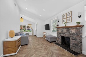 A modern living room with a fireplace, a sofa, a coffee table, and a television.