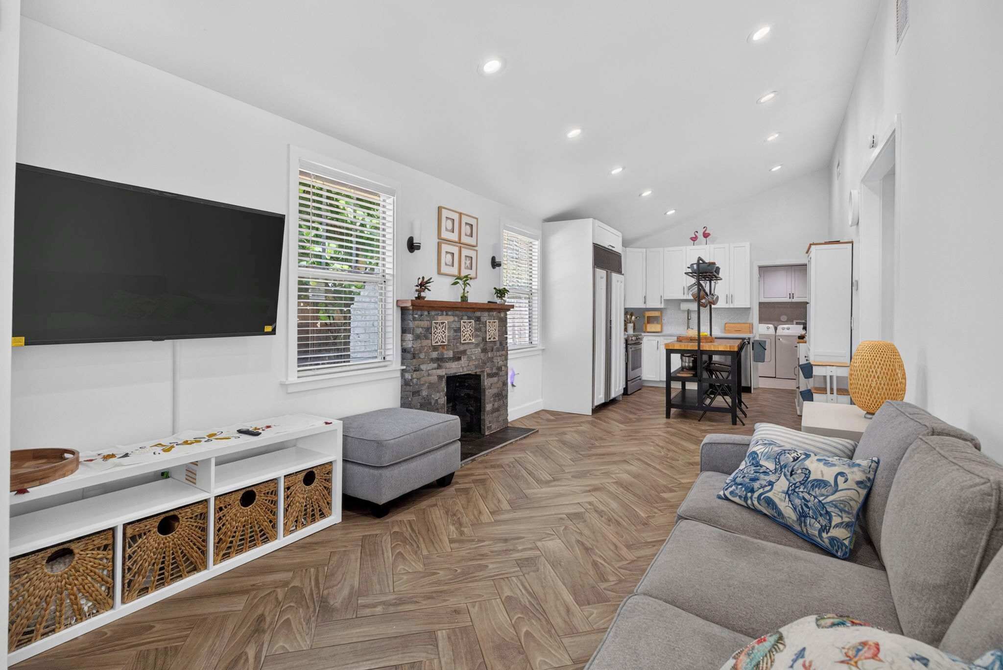 A modern living room with a fireplace, a flat-screen TV, and a herringbone-patterned floor.