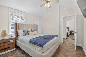 A bedroom with a bed, bedside table, and a ceiling fan. - The Banana Cabana - Cozy Cottage (West Palm Beach)