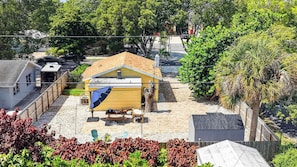 A residential property with a yellow house, a covered patio, and a fenced yard. - The Banana Cabana - Cozy Cottage (West Palm Beach)