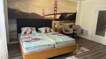 Un dormitorio con cama, una silla, un mural en la pared del Puente Golden Gate y una puerta.