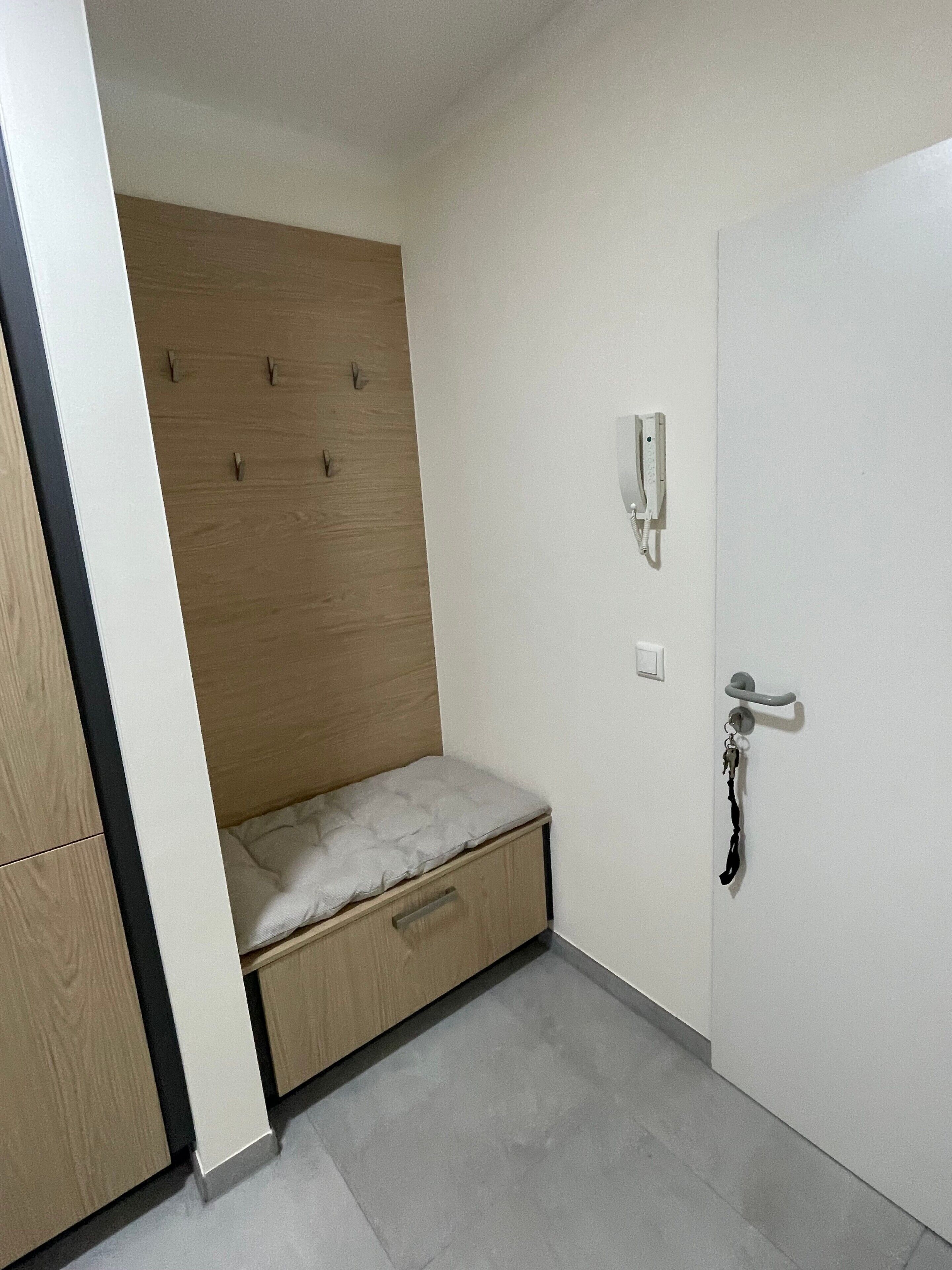 A bedroom with a built-in bed, a bedside telephone, and a door with a handle.