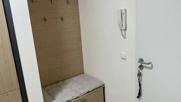 A bedroom with a built-in bed, a bedside telephone, and a door with a handle.