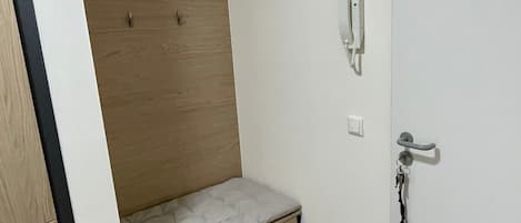 A bedroom with a built-in bed, a bedside telephone, and a door with a handle.