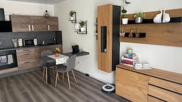 Eine moderne Küche mit Holzschränken, einem Essbereich mit Tisch und Stühlen sowie einem eingebauten Regal mit Pflanzen.